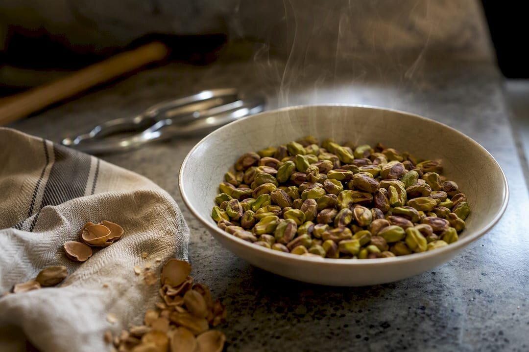 Een kom met vers geroosterde pistachenoten, waar nog stoom uit opstijgt